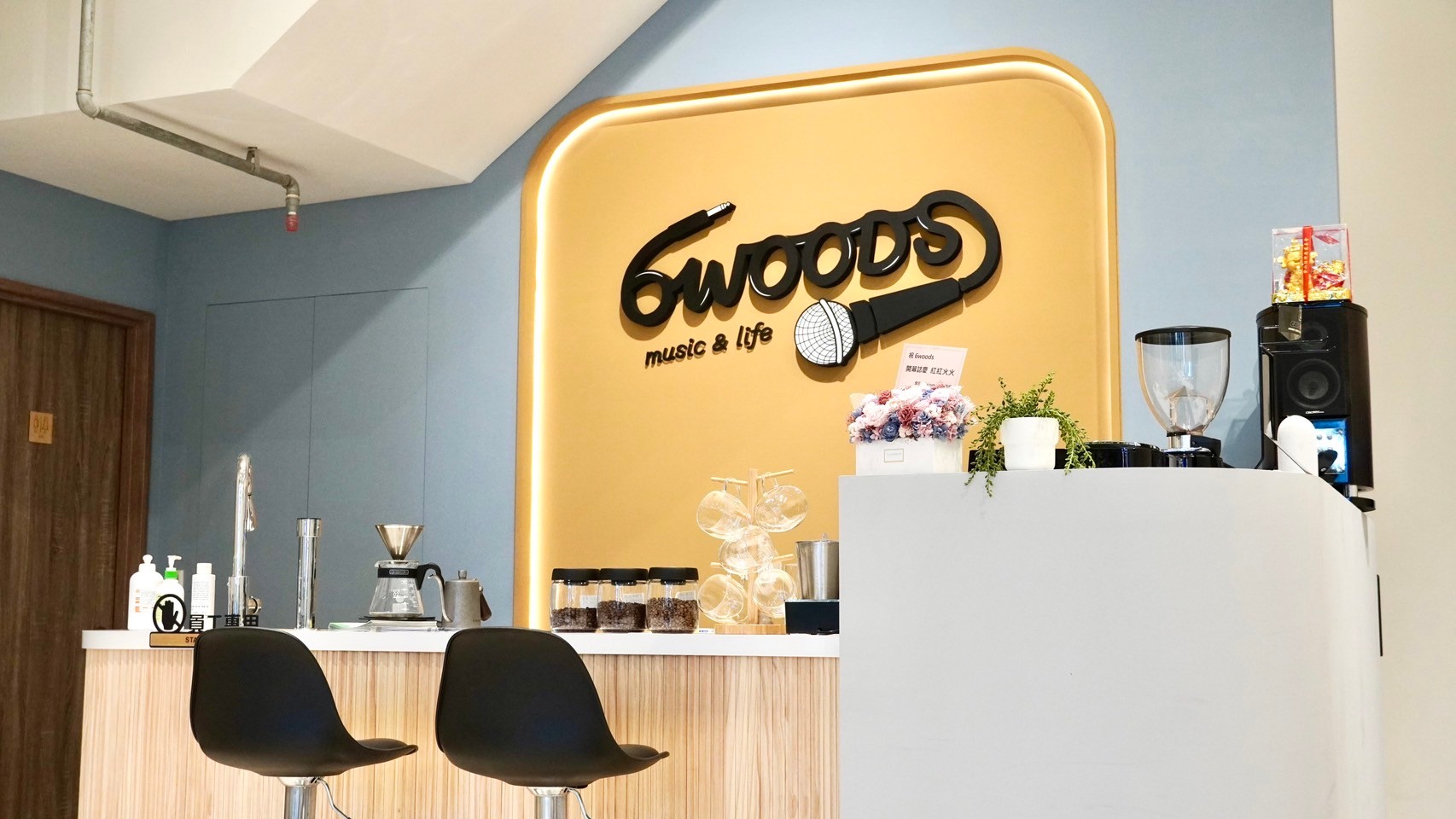 6WOODS 音樂教室溫馨休息交流區，木質吧檯搭配品牌牆，營造放鬆自在的氛圍